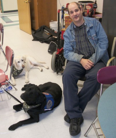 Chris Cotreau with his dogs, Dallas (back left) and Tanner (front left), who were specially trained by Paws with a Cause.